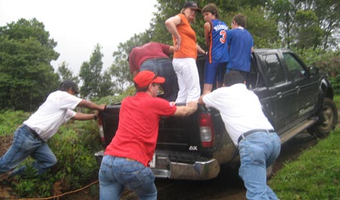 Men pushing truck up dirt road