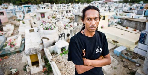 Julinho Ximenhes stands in front of graves at cemetery in Dili