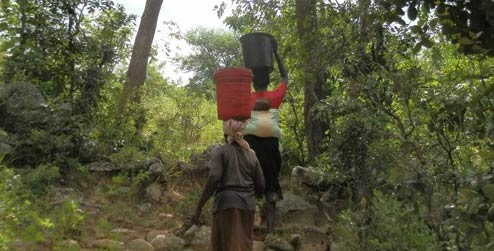 Rebecca Masimbira carrying water up hill