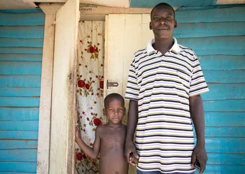 Oranus and his son outside their home in Gens de Nantes, Haiti. (©Fran Afonso/Progressio)