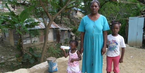 A woman and her children in front of a house in Santiago, Dominican Republic