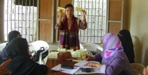 Krishna Karkee holding up notes during workshop in Aden