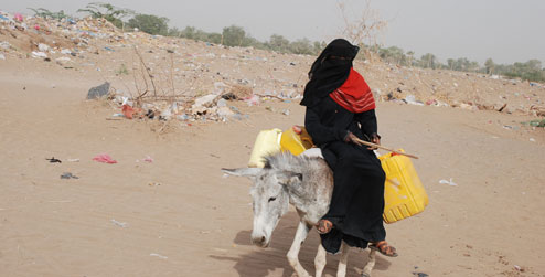 A woman travelling on a donkey to collect water
