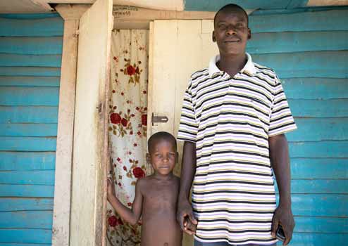 Oranus and his son outside their home in Gens de Nantes, Haiti. (©Fran Afonso/Progressio)