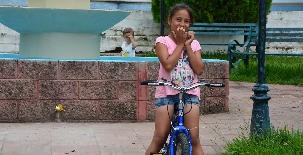 Local girl playing on a bicycle outside the Catholic Church