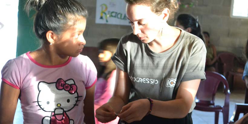 Giulia teaches a community member how to make jewellery with paper