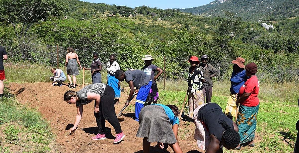 The volunteers working with the beneficiaries to clear the grounds