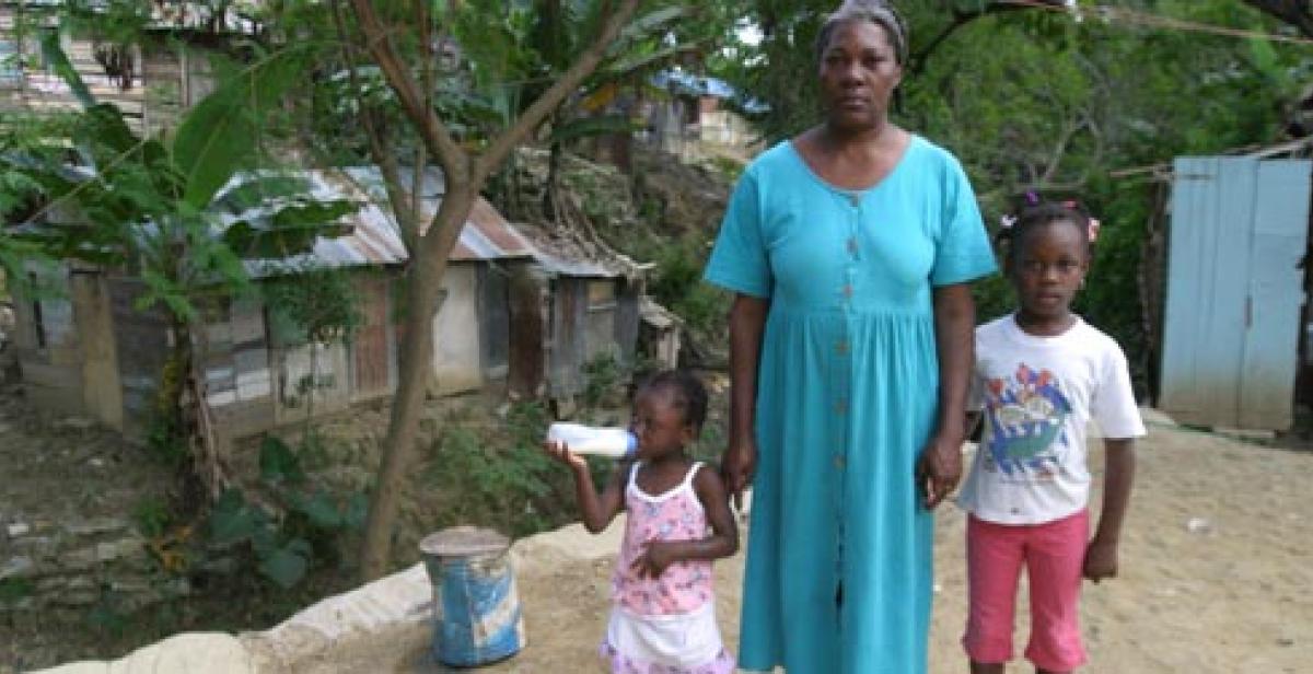 A woman and her children in front of a house in Santiago, Dominican Republic