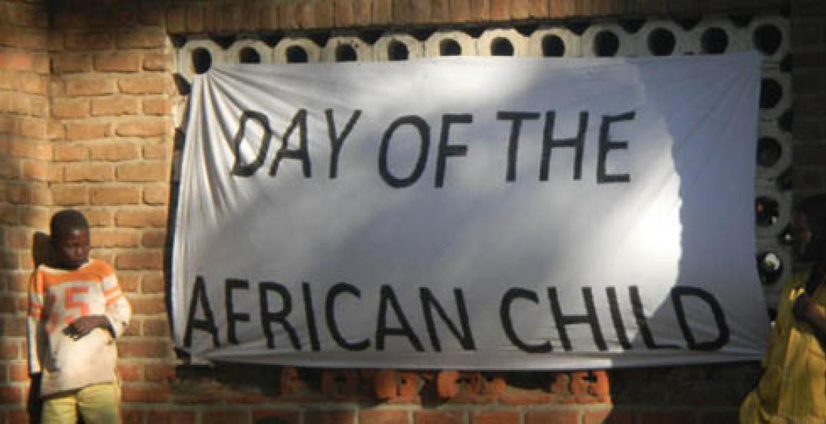 Boy stands beside &#039;Day of the African Child&#039; banner