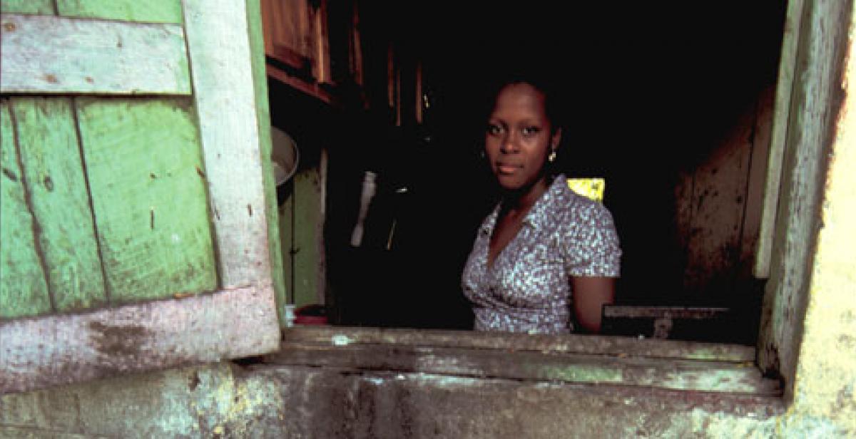 Haitian woman looking out of house window