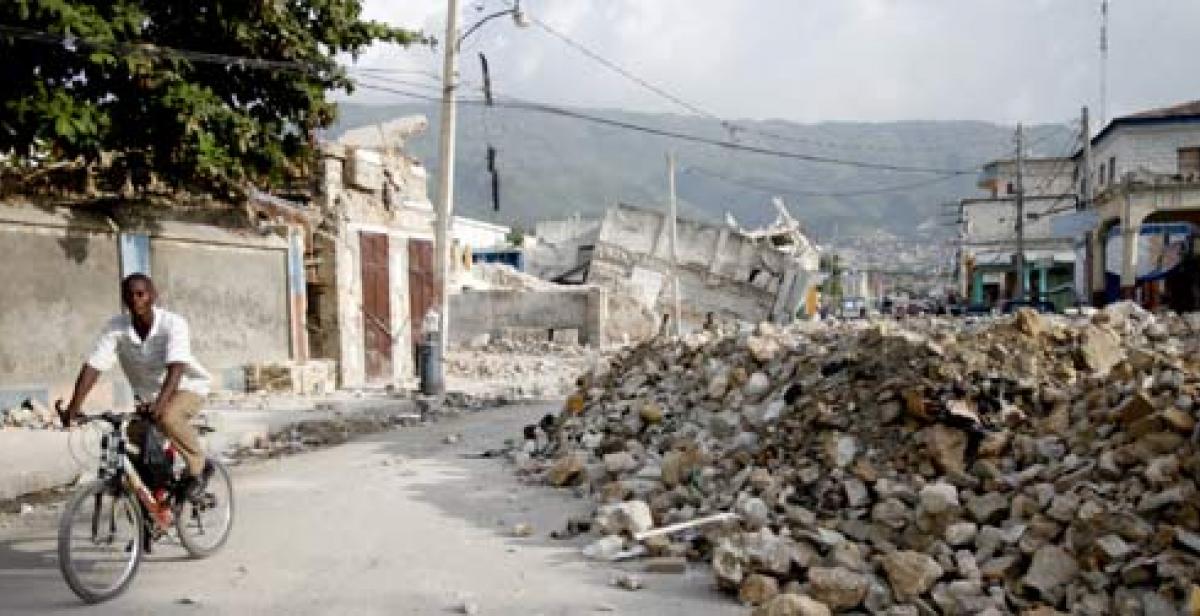 A man riding his bike past the rubble left by the Haiti earthquake.