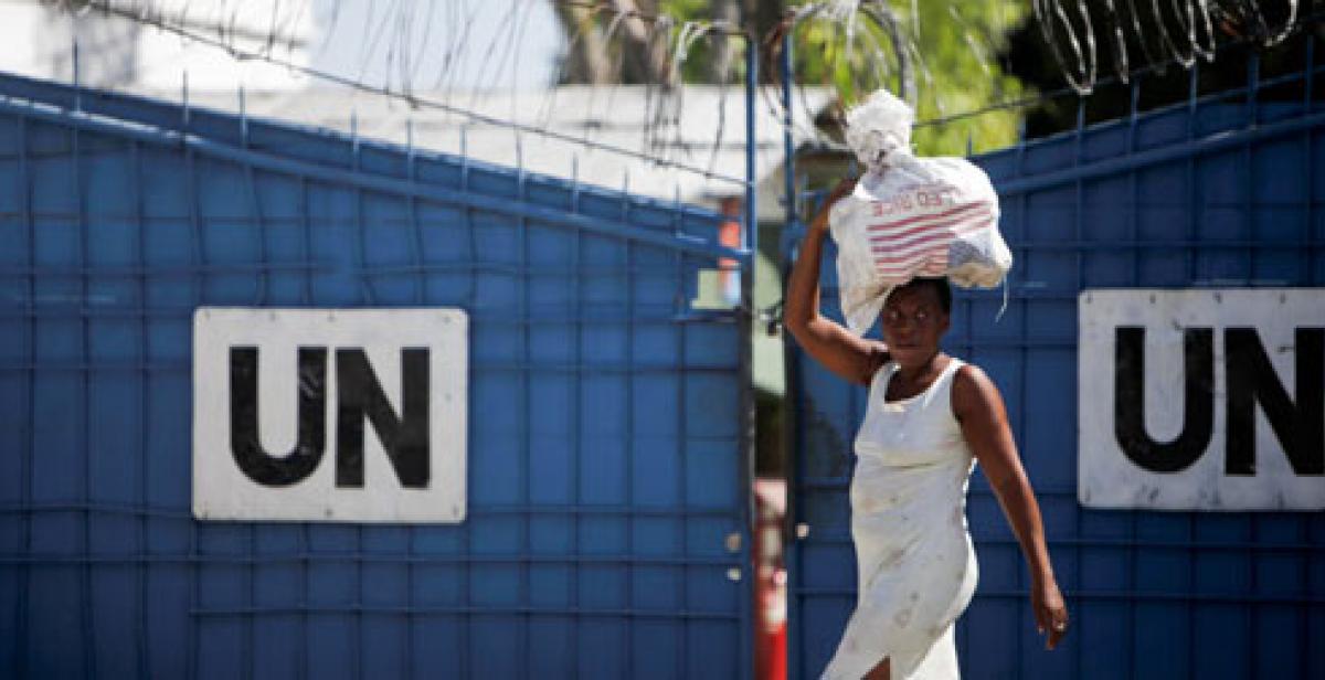 A woman walks by a UN base carrying a bag of rice in Port-Au-Prince, Haiti, 2010