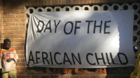 Boy stands beside 'Day of the African Child' banner