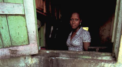 Haitian woman looking out of house window