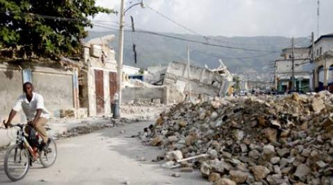 A man riding his bike past the rubble left by the Haiti earthquake.