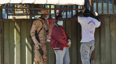 Three people wait at the border in Jimaní