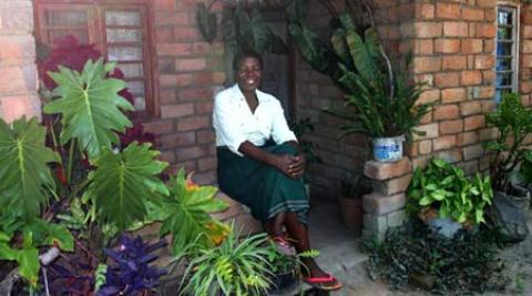 Portrait of Nifa Chumachiyenda, a farmer in Malawi, outside her house