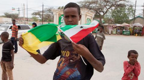 A young man holds flags on a Hargeisa street