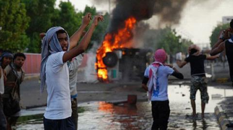 People protest in front of burning vehicle in Aden Yemen